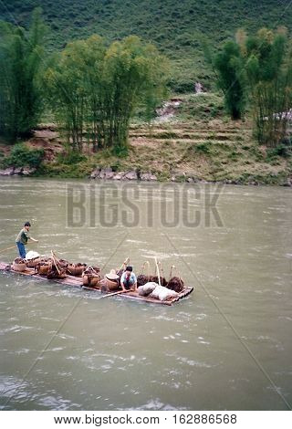 Two young men transport goods on a bamboo raft on the Li River, between Yangshuo and Guilin, China, circa 1987.