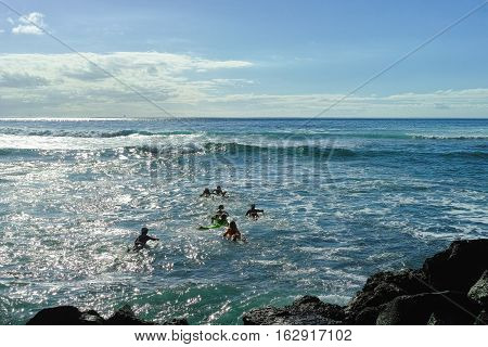 Surf school - several surfboarding students headed into an ocean swell on Tenerife Spain