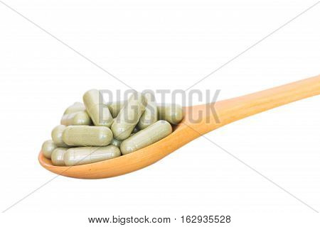 Green Herb Powder Capsules On Wooden Spoon