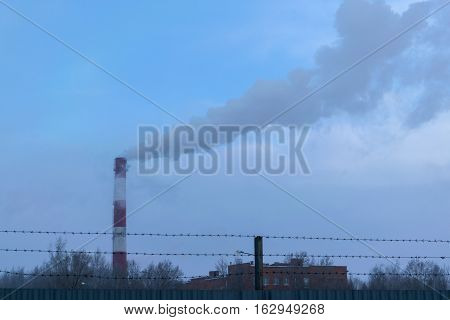 high pipe CHP on the background of blue sky fog smog and out clouds of thick smoke pipe red-and-white it's cold outside