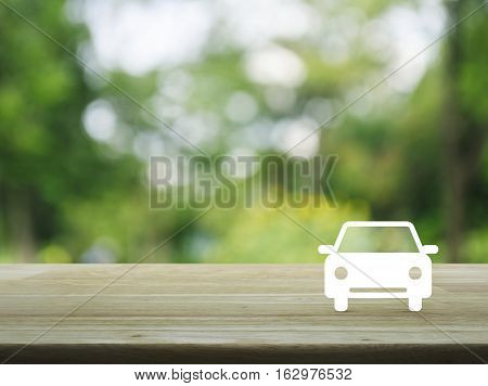 Car flat icon on wooden table over blur green tree background Business service car concept