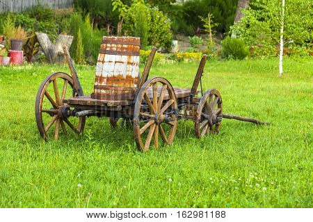 Old wooden cart with a keg on the green grass