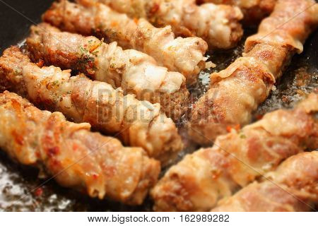 Roasted meat in a pan with bacon chevapchichi. Photo with bokeh effect.