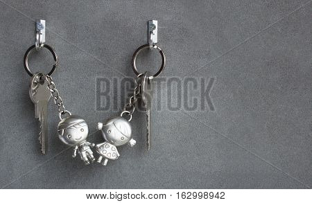 Keyrings boy and girl pulling hands. Lovers keychains, love. Gray background