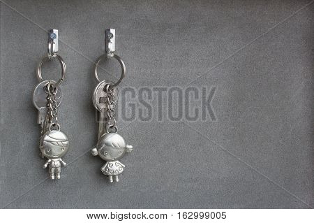 Keyrings boy and girl pulling hands. Lovers keychains, love. Gray background