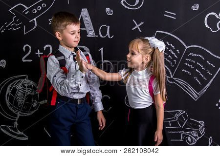 School Mates Standing Before The Chalkboard As A Background With A Backpack On Their Backs Claping T