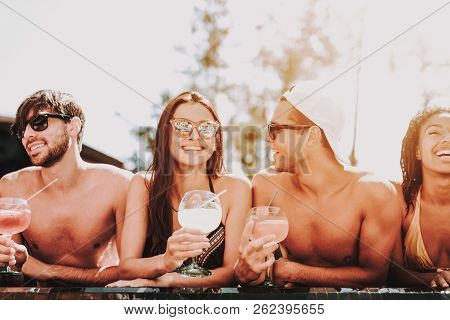 Young Smiling Friends With Cocktails At Poolside. Group Of Young Happy People Holding Glasses With C
