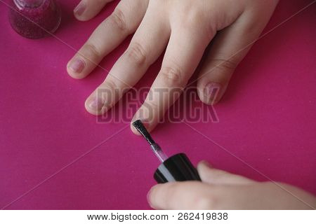 Children's Hands Paint Their Nails With Pink Shiny Nail Polish. Children's Manicure. Glamorous Pink 