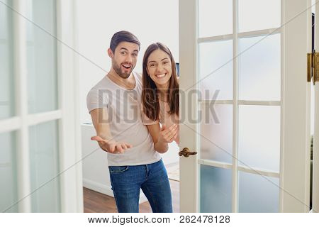 A Couple With Smiles Opens The Door To Their House.