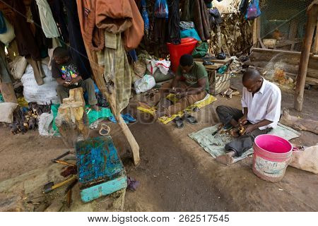 TANZANIA, EAST AFRICA - APRIL 2018 : Local Tanzanian men carving wood on the ground at Mto wa Mbu village, Arusha Region, Tanzania on April 13, 2018.