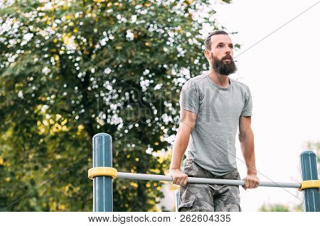 Workout And Outdoor Exercise. Man Doing Pull Ups. Chest Muscles And Biceps Training.