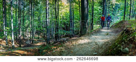 Mountain biking women and man riding on bikes in early spring mountains forest landscape. Couple cycling MTB enduro flow trail track. Outdoor sport activity.