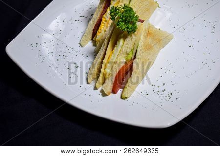 Sandwich With Ham, Cheese, Tomatoes, Lettuce, And Toasted Bread. Above View Vintage On Black Backgro
