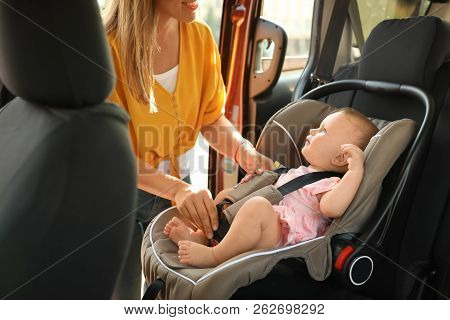 Mother Fastening Baby To Child Safety Seat Inside Of Car