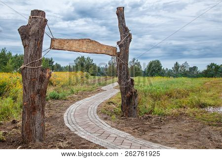 Old Wooden Sign Hanging Between Two Pillars On The Ropes Outdoor On Gloomy Autumn Day