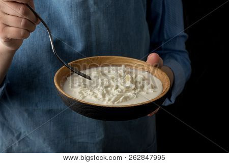 Woman In Blue Apron Holding Bowl With Stracciatella Mozzarella Cheese On Dark Background