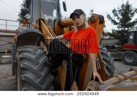 Beautiful Fashionable Young Stylish Woman With Black Cap In A Fashion Orange T-shirt And Black Pants
