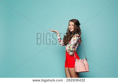 Lovely Girl In Red Shorts And Shirt Presenting Something On Her Arm,