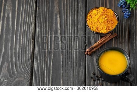 Turmeric And Spice Herbal Tea On Wooden Background. A Cup With Ground Turmeric, Cinnamon And Pepper,