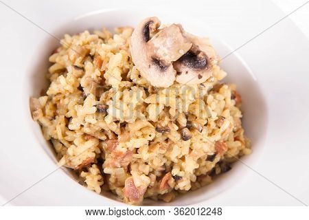 Risotto With Button Mushroom And Bacon Decorated With Mushroom On A Plate On A White Background