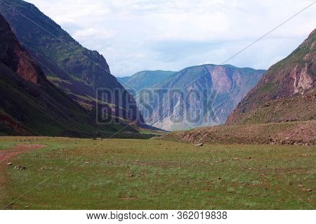Beautiful Green Meadow With Gorge And Mountains In The Distance. A Magical Photo Of Altai Nature. Be