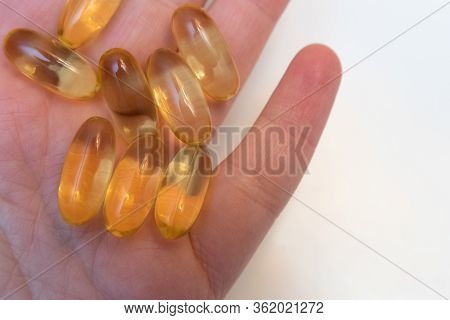 Vitaminen Omega 3 Fish Oil In Capsules In Hand On Beige Background.