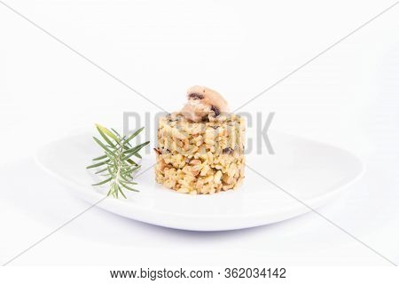 Risotto With Button Mushroom And Bacon Decorated With A Mushroom And Rosemary Twig On A Plate On A W
