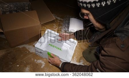 Strasbourg, France - Mar 3, 2020: Overhead View Of Worker Male Unboxing Parcel Containing New Best I