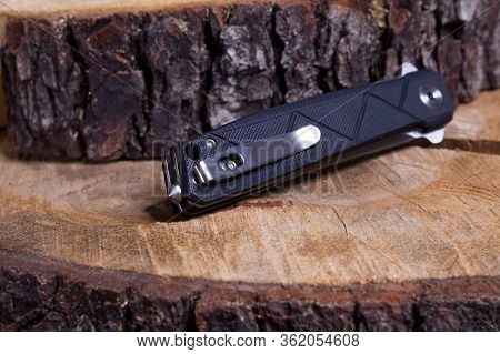 Folding Pocket Knife In The Folded Position. Folded Knife On A Wooden Surface. Clip And Cullet On Th