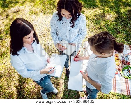Young Beautiful Girls Drawing The Pictures In Sketchbook.