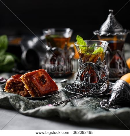 Tea Armud In Turkish Style With Lemon. Served On A Silk Tablecloth With Baklava And Fruit-cherries A