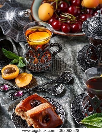 Tea Armud In Turkish Style With Lemon. Served On A Silk Tablecloth With Baklava And Fruit-cherries A