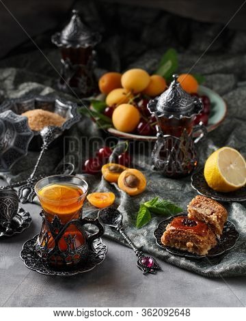 Tea Armud In Turkish Style With Lemon. Served On A Silk Tablecloth With Baklava And Fruit-cherries A