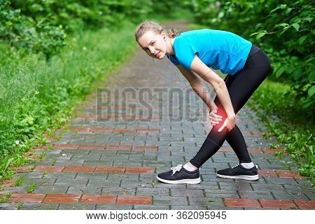 Woman Athlete Runner Touching Knee In Pain, Fitness Woman Running In Summer Park. Healthy Lifestyle