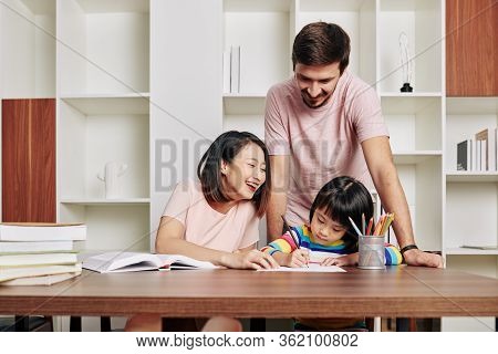 Parents Spending Time With Daughter And Teaching Her Drawing During Quarantine Period
