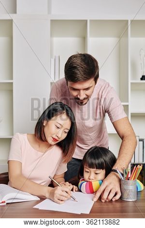 Father Looking At His Wife And Daughter Drawing Pictures For Kindergarten