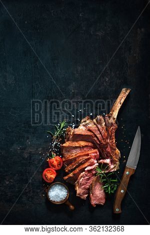 Grilled dry aged tomahawk beef steak sliced on dark background