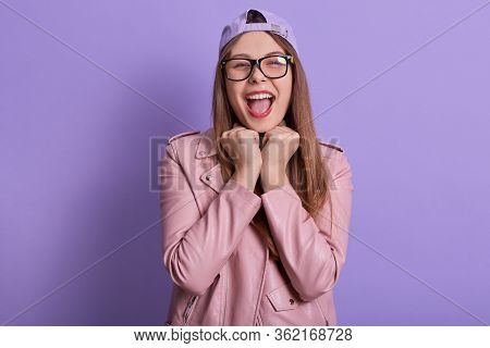 Indoor Portrait Of Charismatic Emotional Female Expressing Her Feelings, Keeping Fists Close To Face