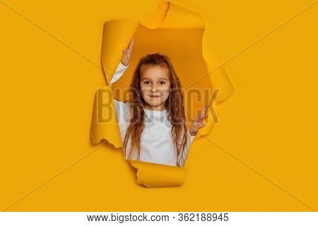 Portrait Of Cute Happy Smiling Caucasian Little Cild Girl Poses In Yellow Paper Hole.