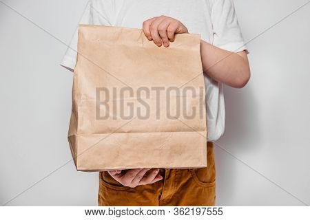 Brown Craft Paper Bag For The Removal Or Delivery Of Goods And Food In Hands On A White Background. 