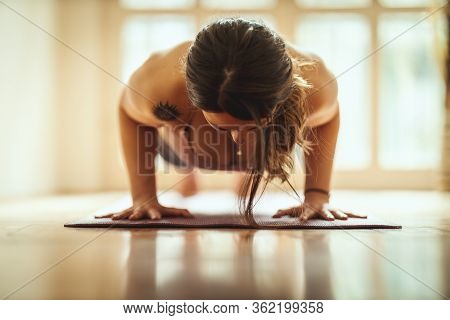 Young Woman Is Doing Yoga Meditation In The Living Room At Home. She Is Meditating On Floor Mat In M