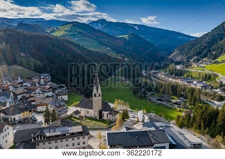 Aerial View Of Valley And Small City With Church, Green Slopes Of The Mountains Of Italy, Trentino, 