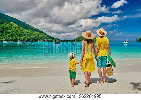 Family on beach, young couple in yellow with three year old boy. Summer vacation at Seychelles. Port Launay, Mahe. 