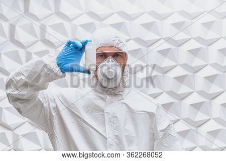 COVID-19 or 2019-nCoV. Doctor microbiologist scientist in a protective PPE suit shows the medicine bottle. Vaccination.