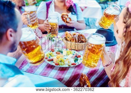 People enjoying food and drink in Bavarian beer garden on a sunny day