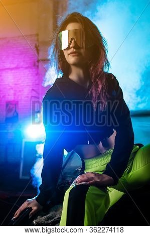 Cinematic Night Portrait Of A Woman In Ski Glasses On A Background Of Pink And Blue Smoke. Modelt Gi