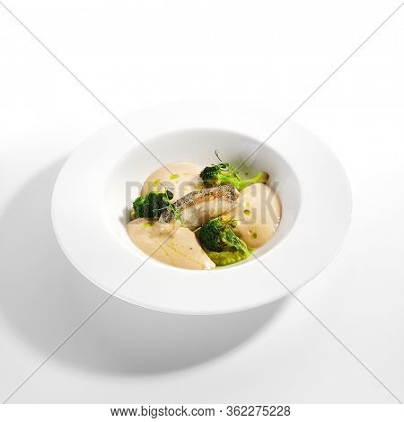 Sea cod fillet close up. Served cuisine. Dish with fish and baked broccoli puree ingredients in white plate isolated. Luxury culinary. Restaurant food portion, delicious supper, main course
