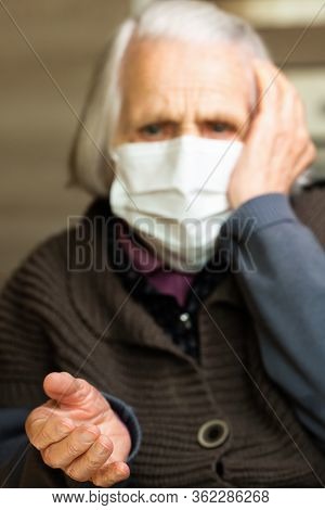 Senior Lady With Hygienic Facial Mask In Difocus. Old Woman With Frightened Eyes. Covid-19 Concept, 