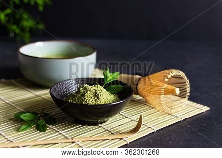 Organic Green Matcha Tea And Tea Accessories On Japanese Mat On Black Background. Japanese Tea Cerem