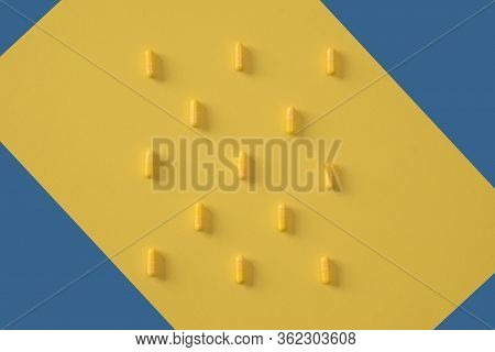 Yellow Capsules Are Laid Out On A Yellow Background With Elements Of A Blue Background. Concept For 